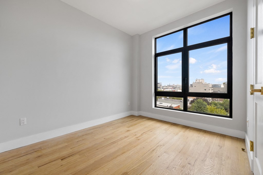 an empty room with a large window and wooden floors